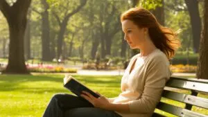 Attractive Woman Reading a Book in a Park Bench