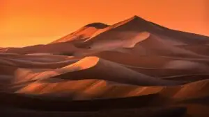 Desert Dunes Under Orange Sunset