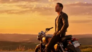 Fit Guy Resting on His Motorcycle at Sunset