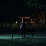 Girl Sitting Alone on Empty Bench at Night