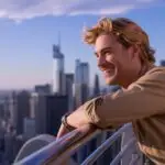 Guy Leaning on Metal Railings Overlooking the City