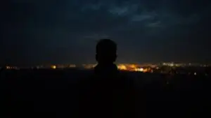 Man Looking at Distant Night Lights