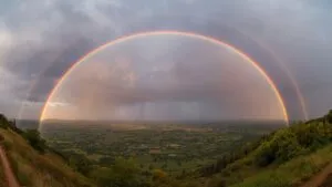 Rainbow Arching Over Valley After Rain