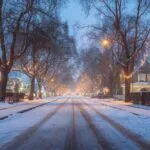 Snow Falling on Quiet Street With Warm House Lights