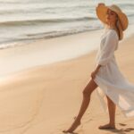 Woman in Hat Standing on Sandy Beach