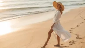 Woman in Hat Standing on Sandy Beach