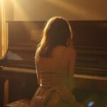 Woman Sitting Beside Piano in Sunlight