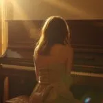 Woman Sitting Beside Piano in Sunlight