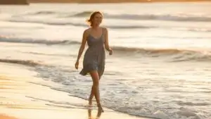 Woman Walking Along Beach With Bare Feet