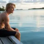 Young Man Sitting on a Pier Looking at the Water