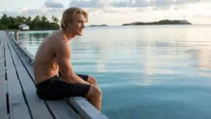 Young Man Sitting on a Pier Looking at the Water