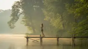 Girl Standing by Lake in Morning Fog