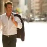 Man Holding Jacket Over Shoulder Walking Down Street