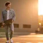 Man Holding Skateboard Under Warm Sunset