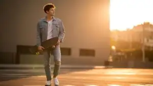 Man Holding Skateboard Under Warm Sunset