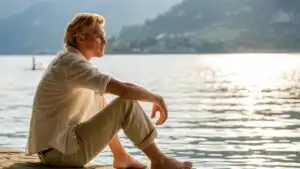 Man Sitting by Lake With Shoes Off Relaxing