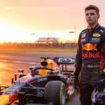 Max Verstappen Standing Beside a Formula One Car at Sunset