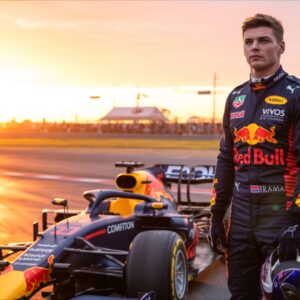 Max Verstappen Standing Beside a Formula One Car at Sunset