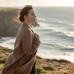 Woman Standing Near Ocean Cliff Looking at Waves