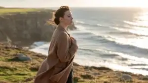 Woman Standing Near Ocean Cliff Looking at Waves