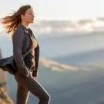Woman Standing on Cliff Edge With Wind in Hair