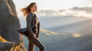 Woman Standing on Cliff Edge With Wind in Hair
