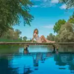 Woman Sitting on Wooden Bridge Above Calm Water