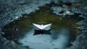 Paper Boat Floating in Rain Puddle