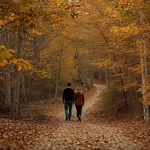 Couple Walking Through Autumn Forest Path