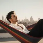 Harry Styles reclining on a rooftop hammock
