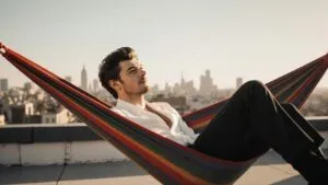 Harry Styles reclining on a rooftop hammock