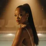 Rihanna Sitting Beside a Pool Under Golden Lights